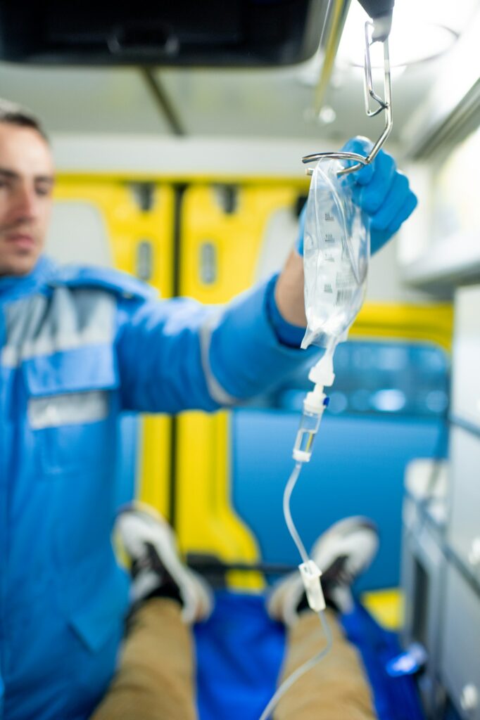 Gloved paramedic putting dropper on holder over sick person in ambulance car